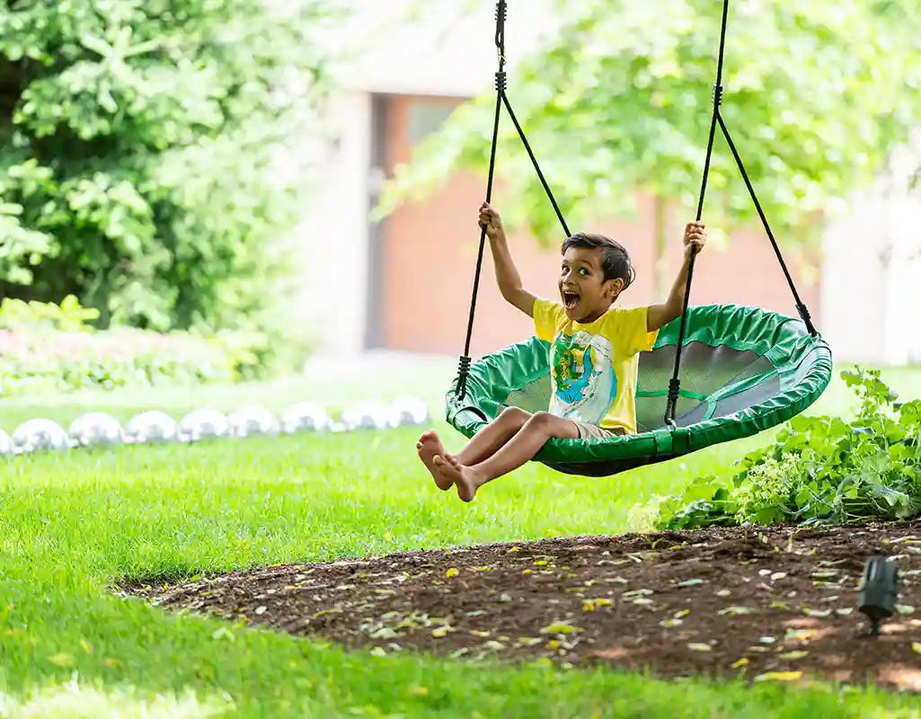boy playing on a round platform tree swing
