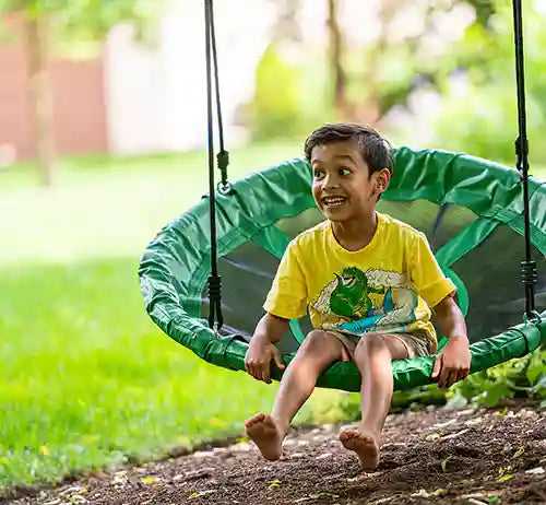 kid sitting on a round platform tree swing
