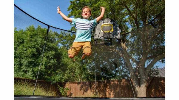 A kid jumping in mid-air on a trampoline. 