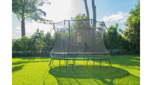 A little girl in a yellow shirt jumping on a Springfree Trampoline.