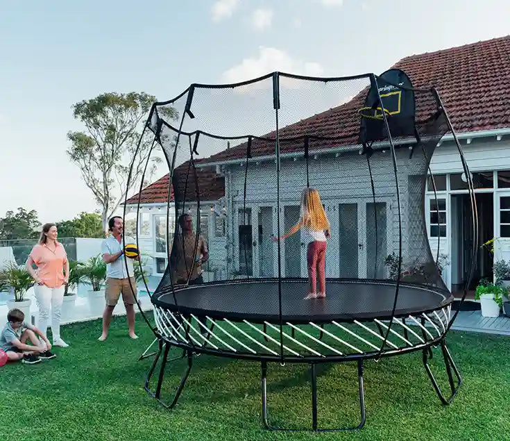 girl standing on a trampoline while her family is watching her