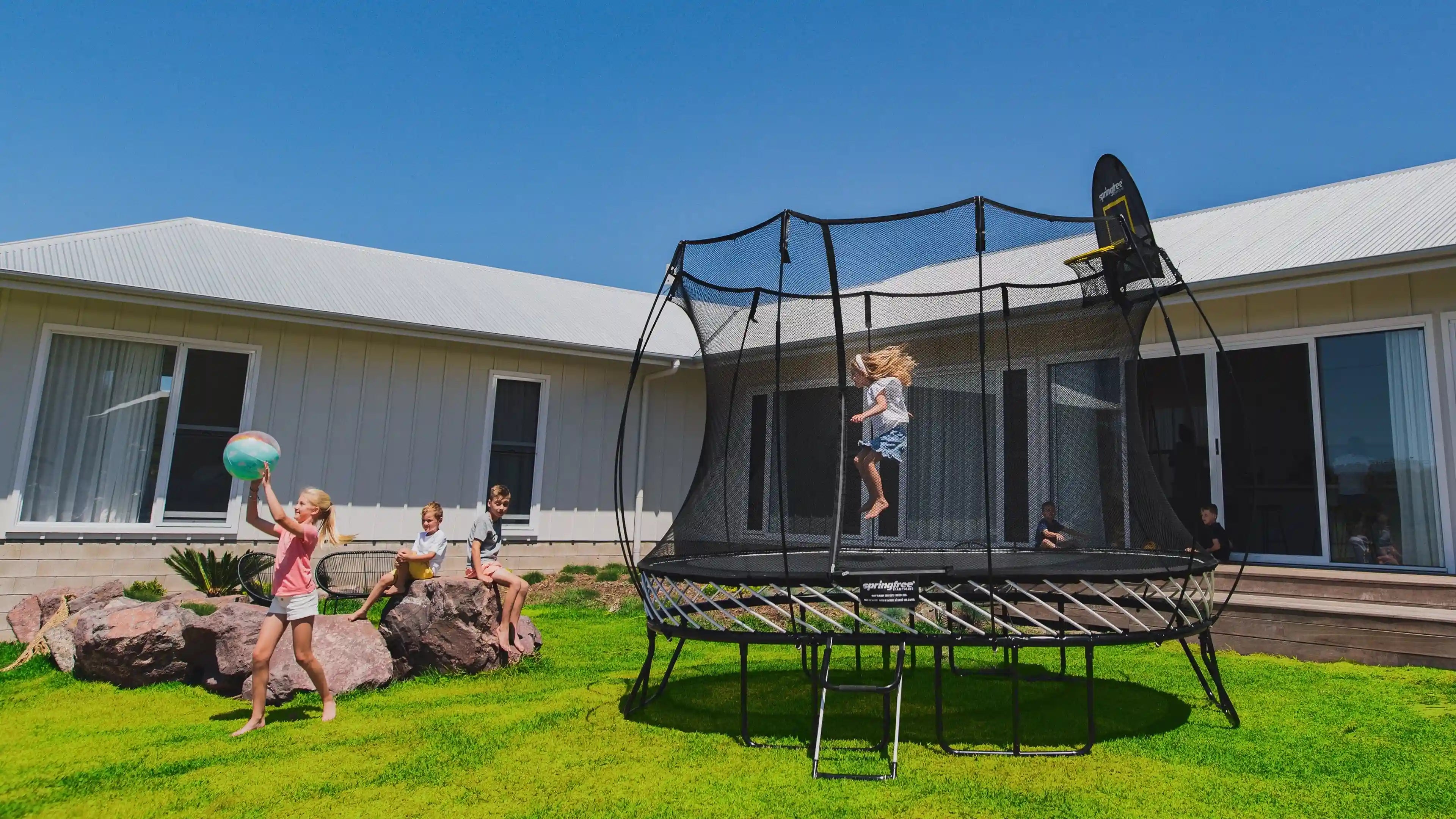 girl jumping on a trampoline with other kids watching him