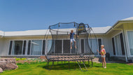 Load image into Gallery viewer, boy jumping high on a trampoline with his sister holding a basketball
