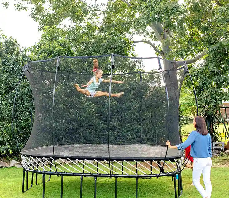 girl jumping very high on an outdoor trampoline